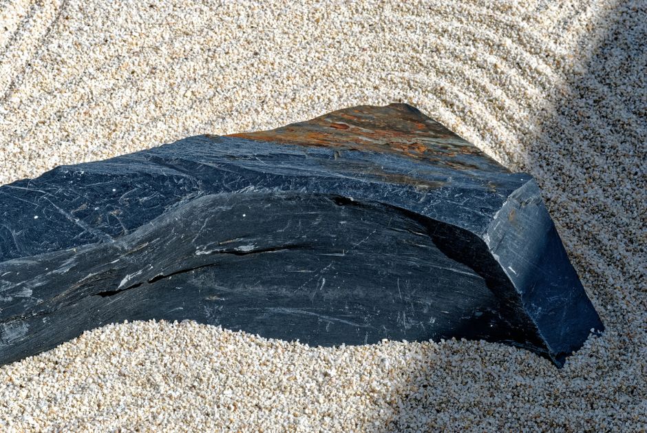 Serene zen garden scene featuring a large rock on meticulously raked gravel.