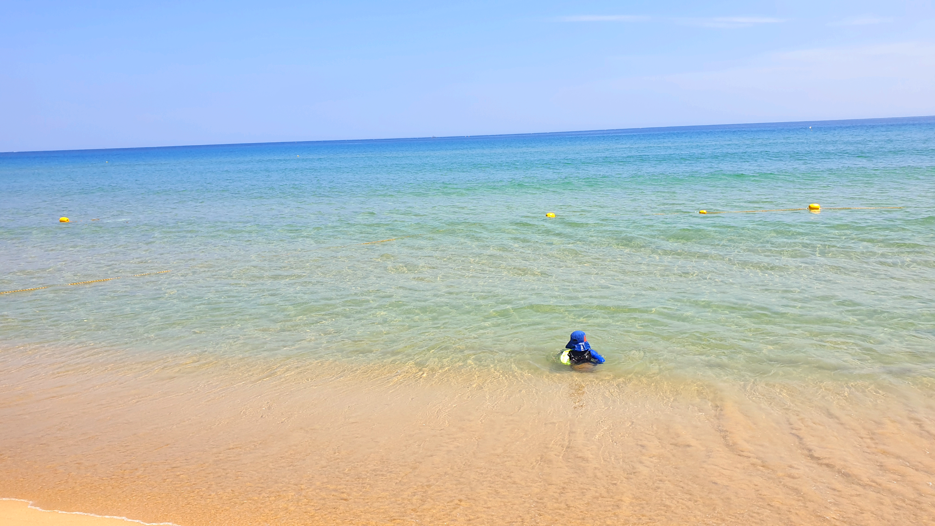 얕은바다물에 아이가 앉아있다.