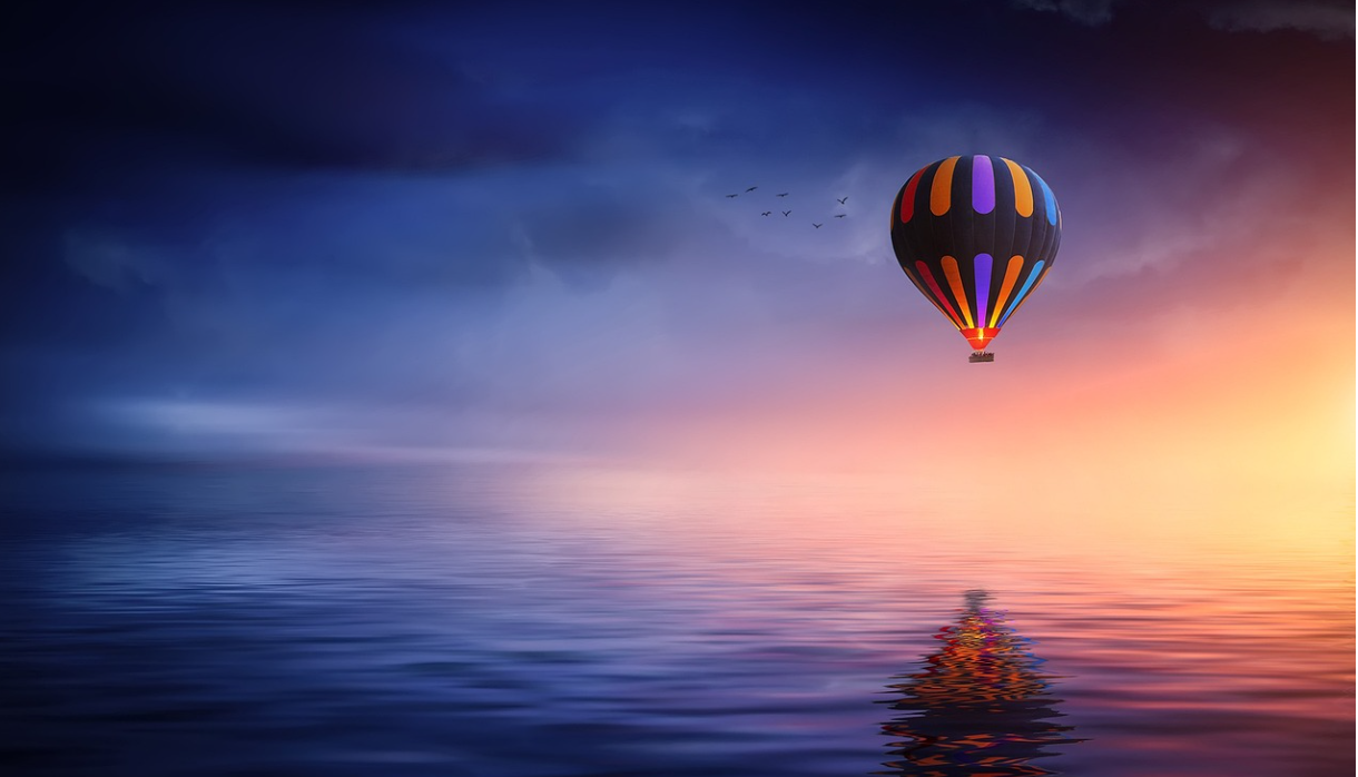 바닷물 위에 떠있는 알록달록한 무늬의 열기구 사진