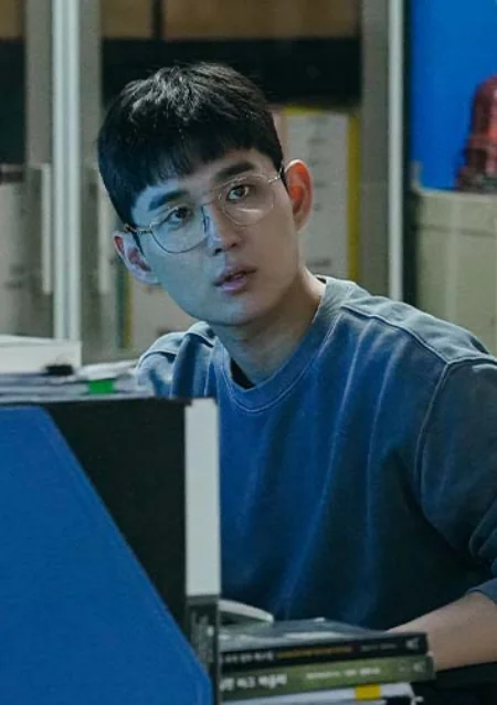 안경을 쓰고 파란 티셔츠를 입고 앉아 있는 힘쎈여자 강남순의 진선규 캐릭터