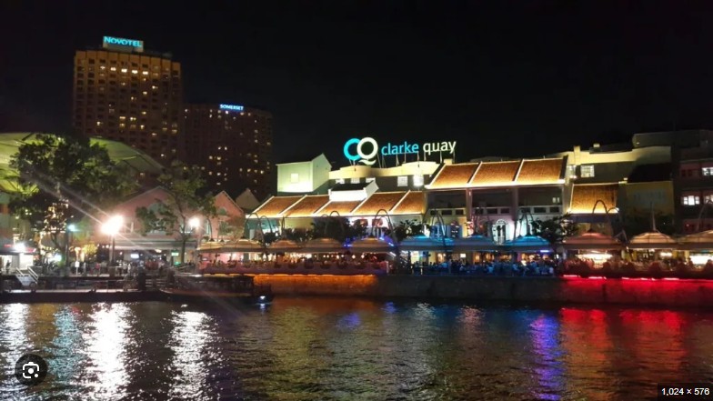 Clarke Quay 로고가 보이는 클락키 건물과 리버사이드의 조명 반사 뷰
