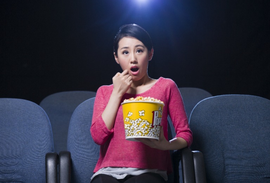 팝콘을 들고 영화를 보며 놀라는 여자의 표정