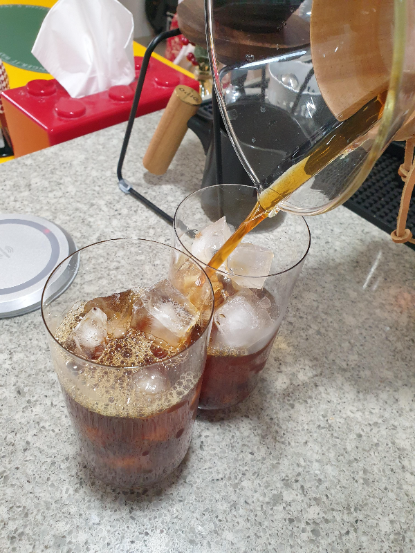 얼음이 담긴 두 개의 컵에 커피를 담는 모습