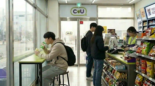 아침에 편의점에서 빵과 우유를 마시고 있는 학생.