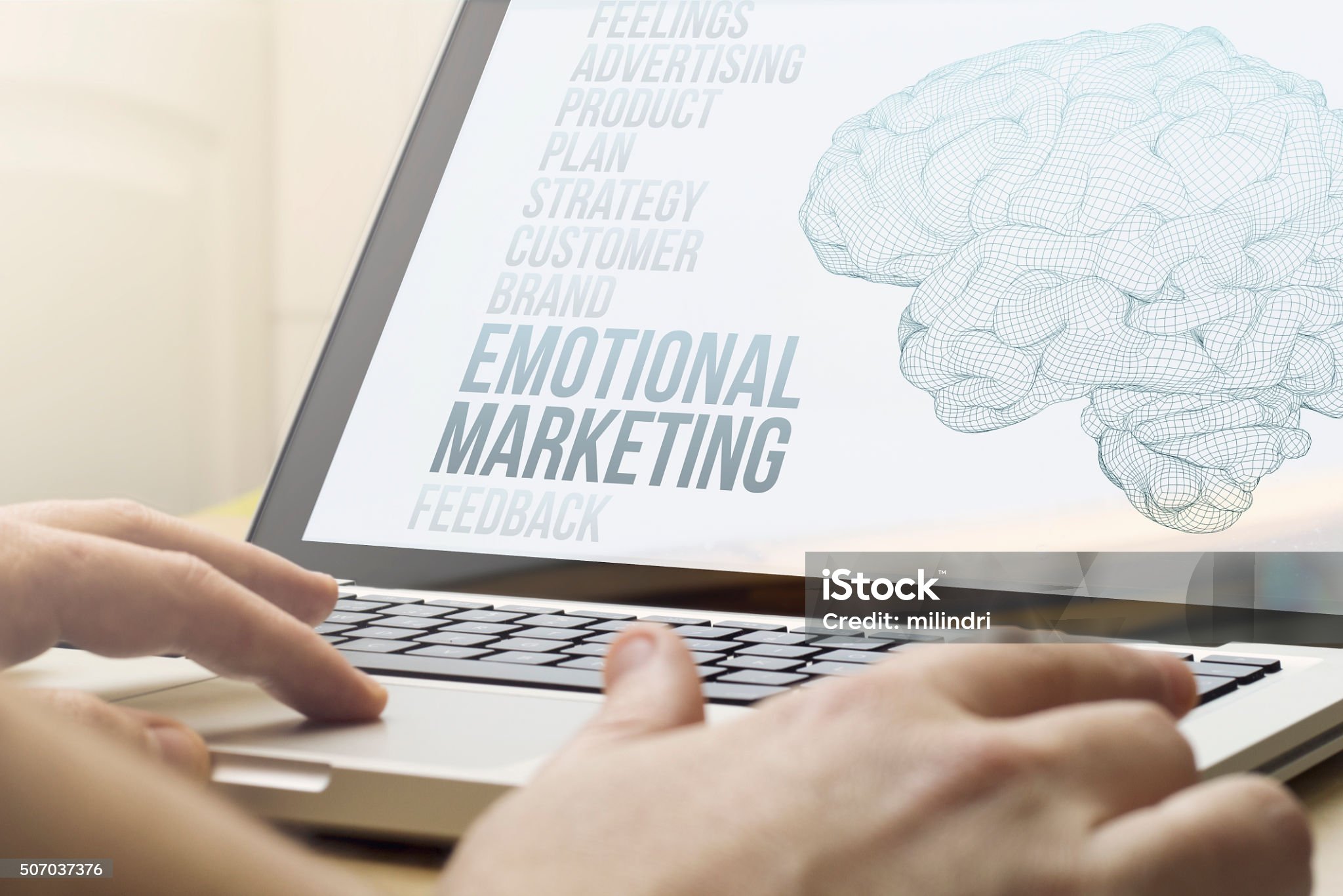 노트북 화면에 emotional marketing 이라고 적혀있는게 떠있고 사람의손과 노트북이 보이는 사진