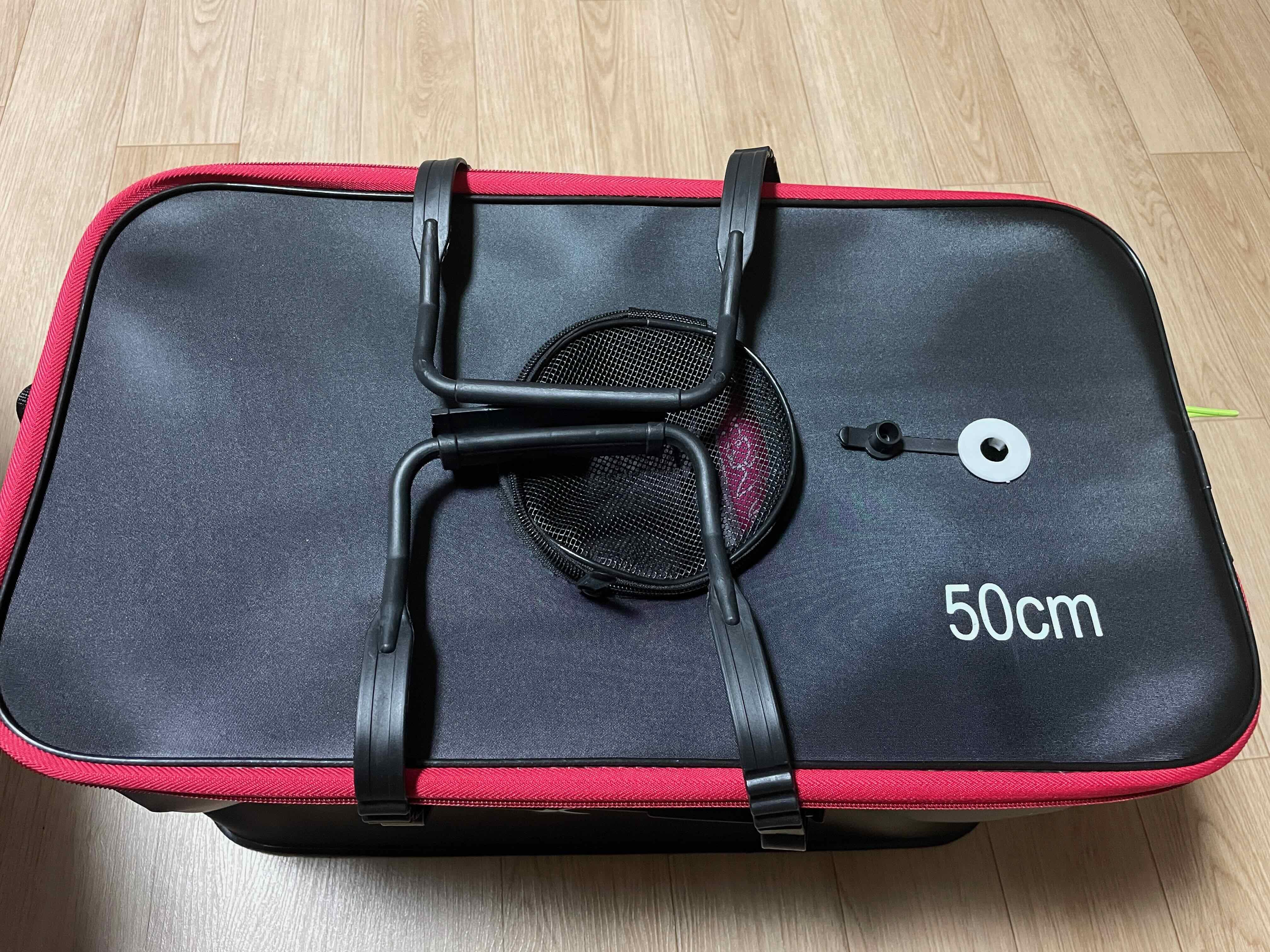 검은 컬러의 가방&amp;#44; 빨간색 띠가 있으며 위에서 바라보고 가운데 홀이 망사로 되어있는 모습