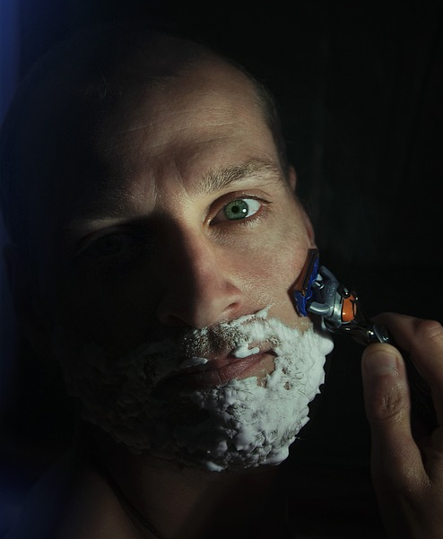 A man is shaving with shaving foam applied.
