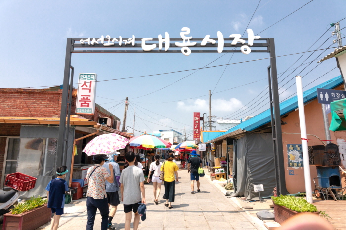 시장입구에 사람들이 우산을 쓰고 들어가고 있다.