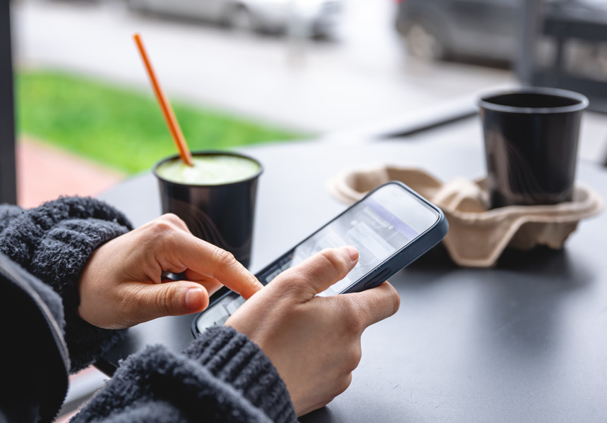 카페에서 커피를 마시며 스마트폰을 보는 모습
