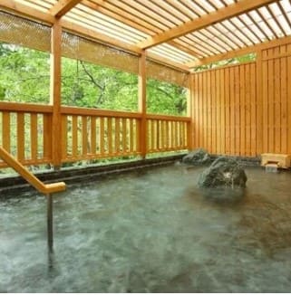 야외 온천장에 물이 있고 그 위로 수증기가 있다.