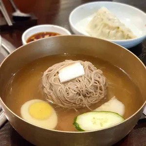놋그릇에 담긴 시원한 평양물냉면, 오이, 고기, 삶은달걀이 함께 어우러집니다.