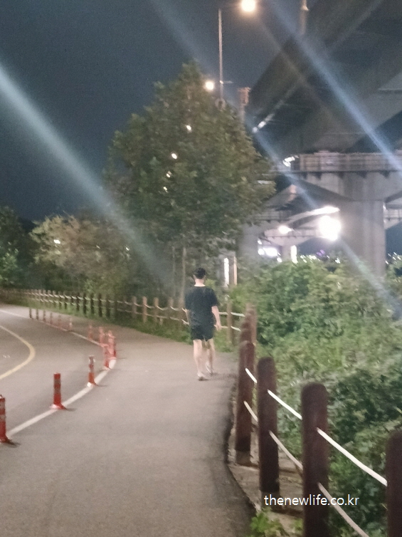 야간 산책로에서 워킹화와 가벼운 운동복을 착용하고 걷는 사람