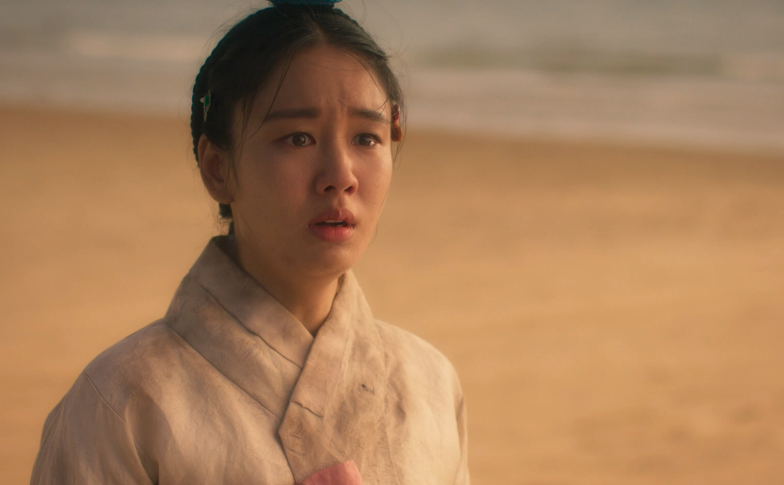 한 여인이 우수에 찬 표정으로 한 곳을 응시하고 있다.