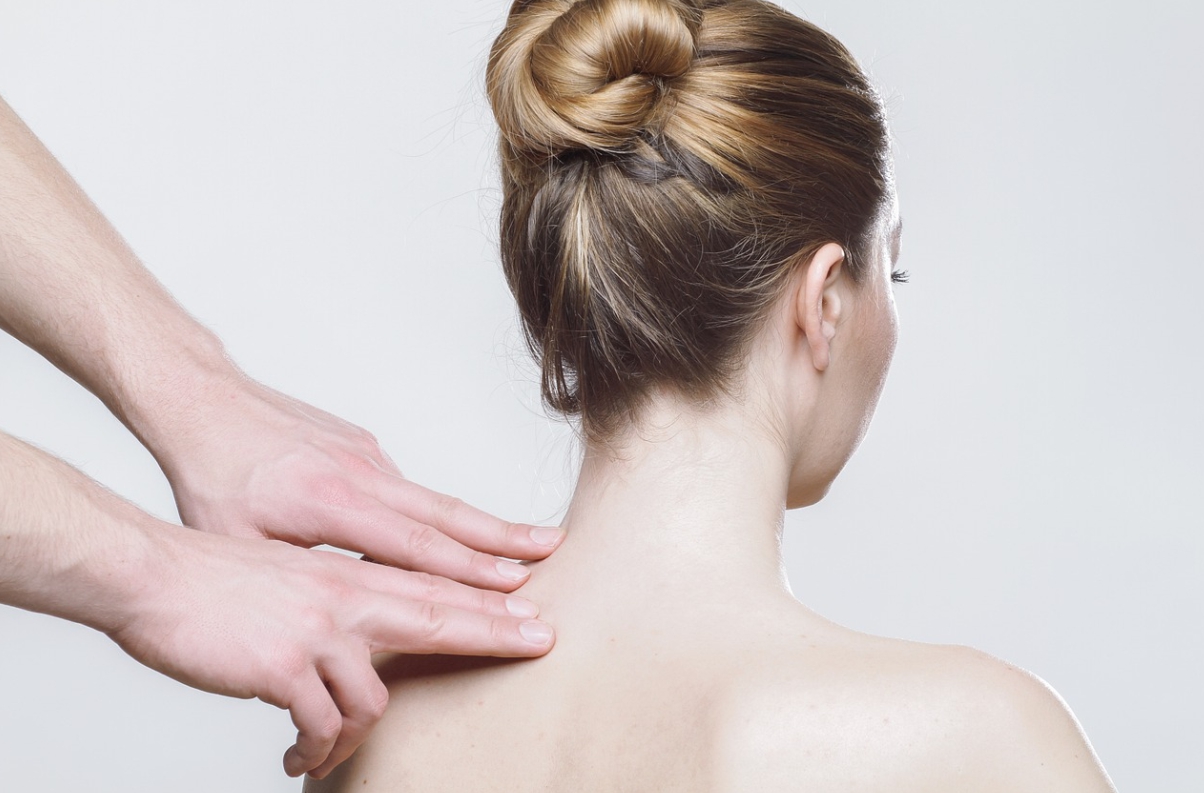 뒤 돌아 상의 탈의한 여성의 왼쪽 어깨를 다른 두 손이 누르고 있는 사진