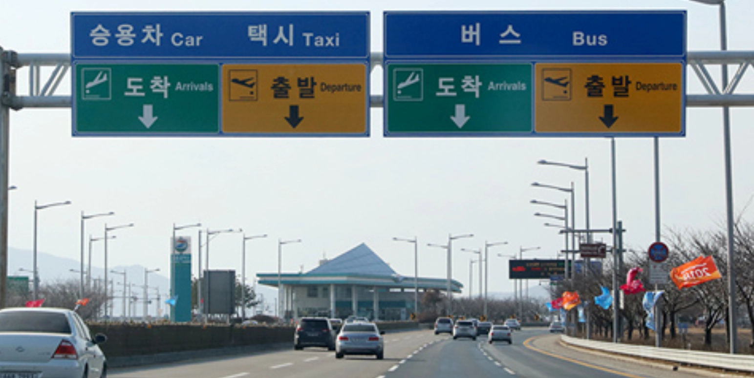 도로에서 파란색&#44; 초록색&#44; 노란색 표지판이 기둥에 걸려있다.