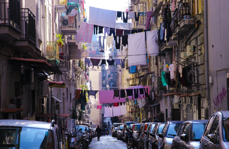 대낮에 양쪽의 건물들 사이로 줄이 연결돼 있고, 줄에는 빨래들이 널어져 있다.(나폴리)