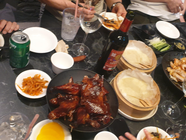 테이블 중앙에 베이징덕과 와인이 보인다.