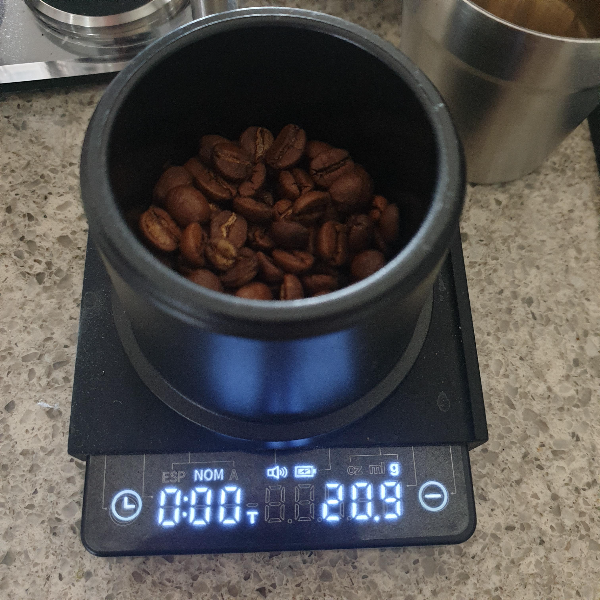 저울 위에 원두가 담긴 통이 있다. 통 안에는 원두가 들어있다. 저울은 20.9g을 가르킨다.