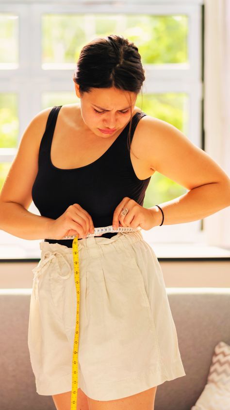 허리둘레를 줄자로 측정하고 있는 여성