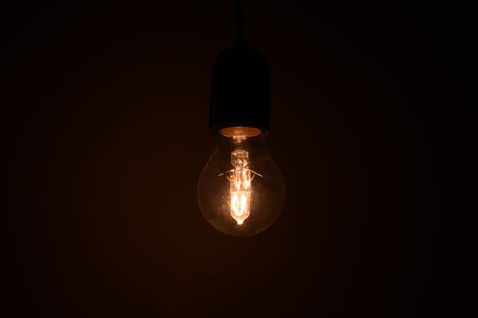 Close-up view of an illuminated light bulb glowing in a dark environment, emitting warm light.