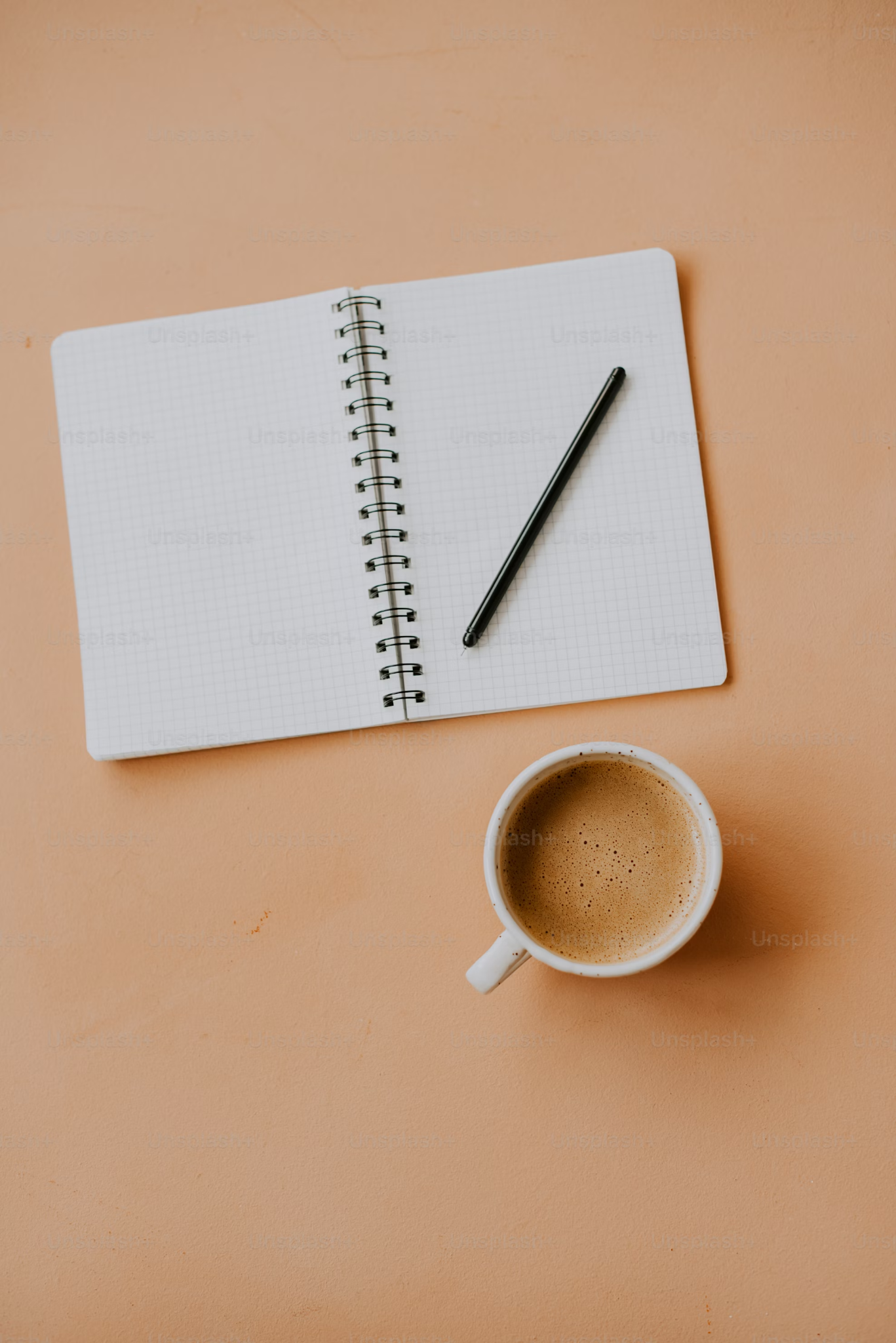 노트와 펜, 그리고 커피 한 잔이 놓인 따뜻한 책상 위