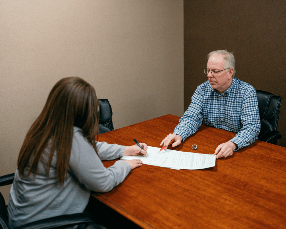 사무실 책상에서 여성과 노년 남성이 주민등록 관련 문서를 작성하는 장면