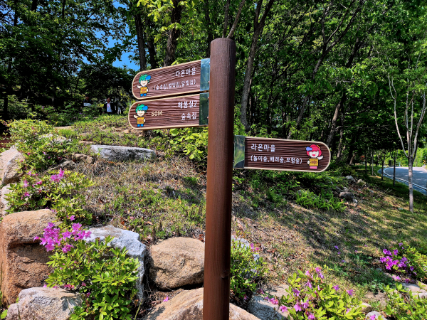 숲길 이정표, 다옴마을, 체험상가, 라온마을 등 다양한 방향을 가리키고 있다