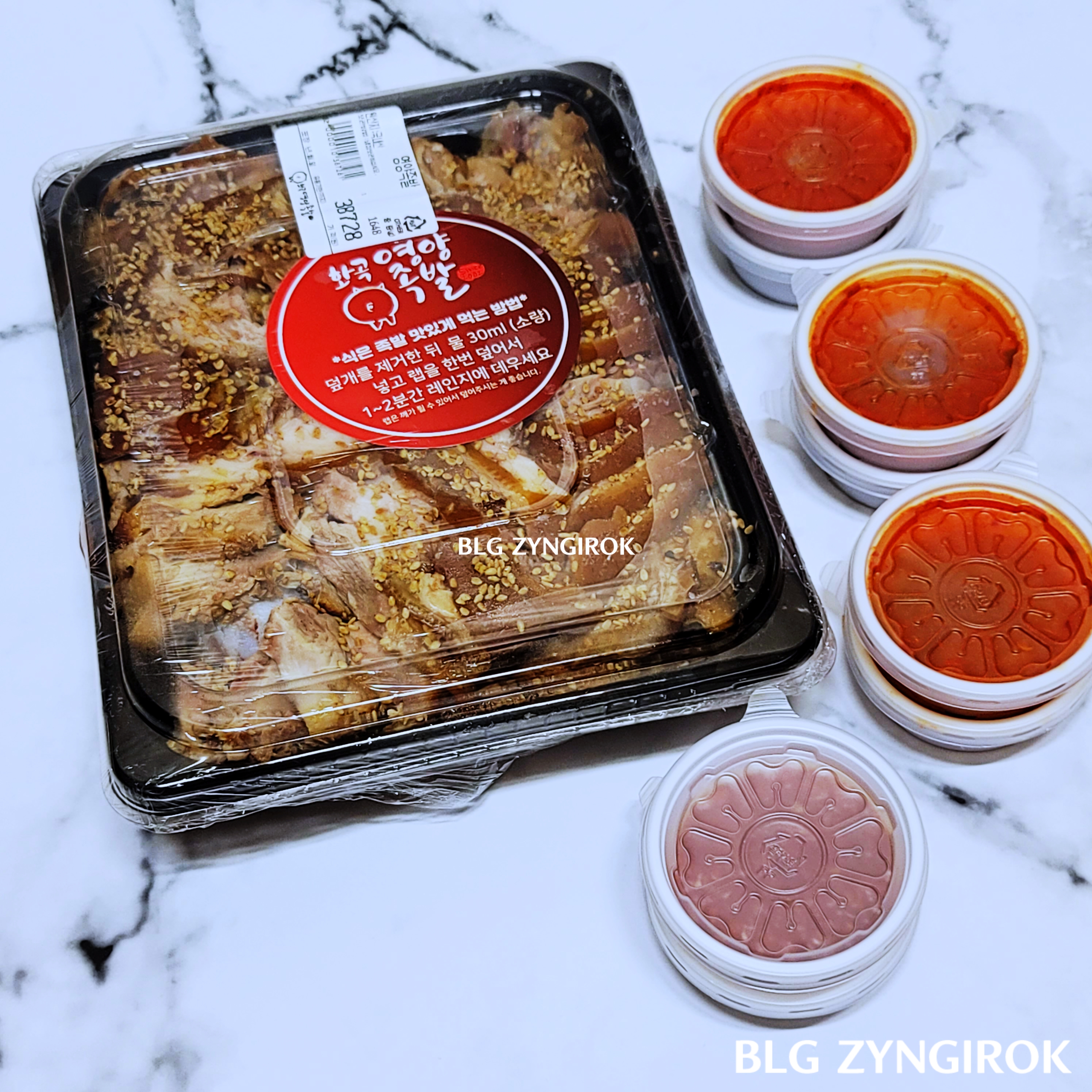 영양족발의-포장-모습이다. 플라스틱-그릇에-담겨진-족발은-랩으로-한번더-싸여있다. 족발오른편에는-플라스틱-소스통들이-놓여있다.