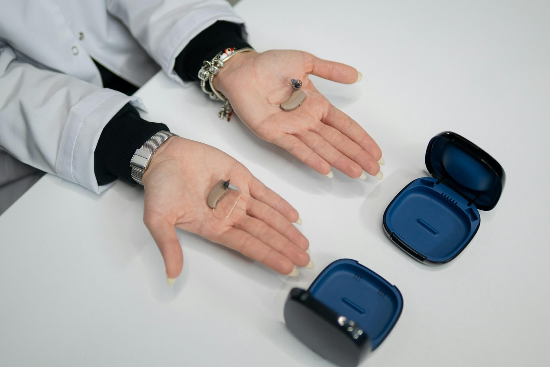 의료인이 두 손에 보청기를 올려 보여주는 모습