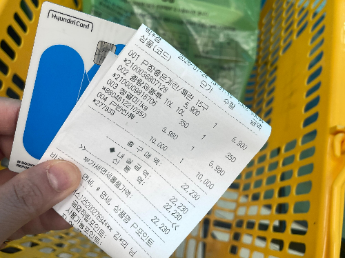 카드와 영수증이 있고, 뒤에는 장바구니에 담긴 규격봉투가 있습니다.