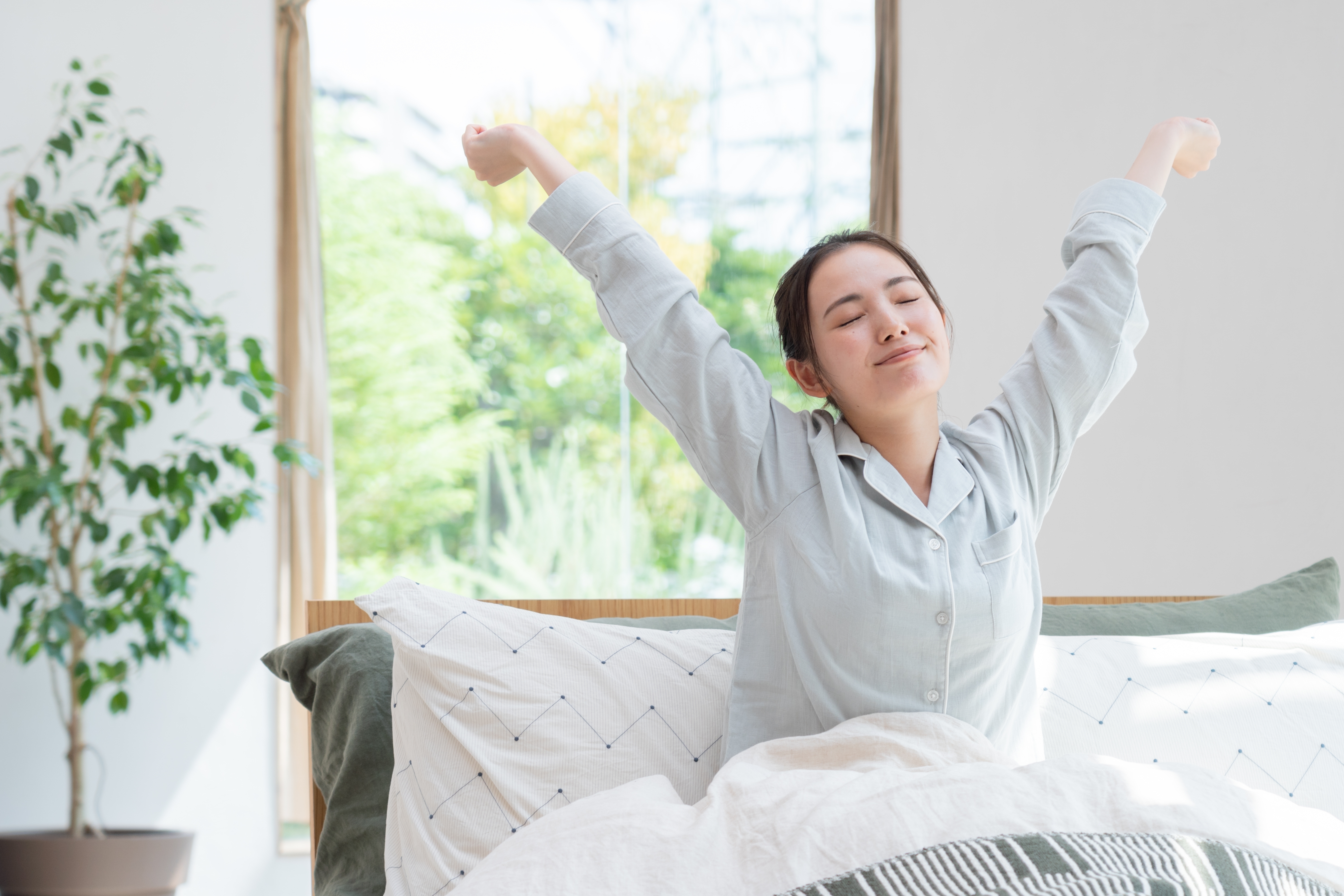 밝은 아침 햇살 아래 기지개를 켜며 상쾌하게 하루를 시작하는 여성 – 숙면 후 활기찬 아침을 맞이하는 모습