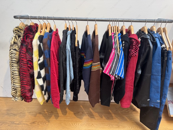 A rack featuring Supreme faux fur jackets, heavy knit sweaters, and technical outerwear inside the Paris store