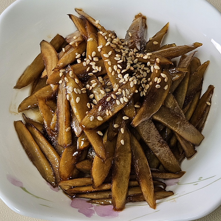 우엉조림 완성하여 접시에 담은 모습. 간장 양념으로 윤기 나게 졸여서 통깨를 위에 뿌려주었다