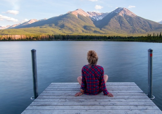 캐모마일차 효능 중 하나인 심신안정을 나타낸 이미지로 사람 한명이 편안한 자세로 강가에서 휴식을 취하고 있는 모습입니다.