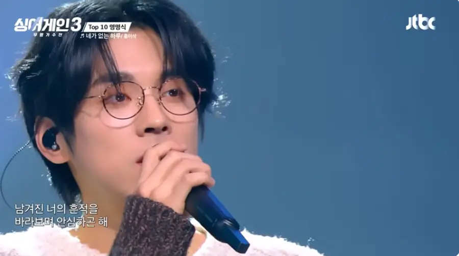 싱어게인3-
파란무대배경 웨이브진 머리 검은색 안경 검은 마이크를 들고 노래하는 58호