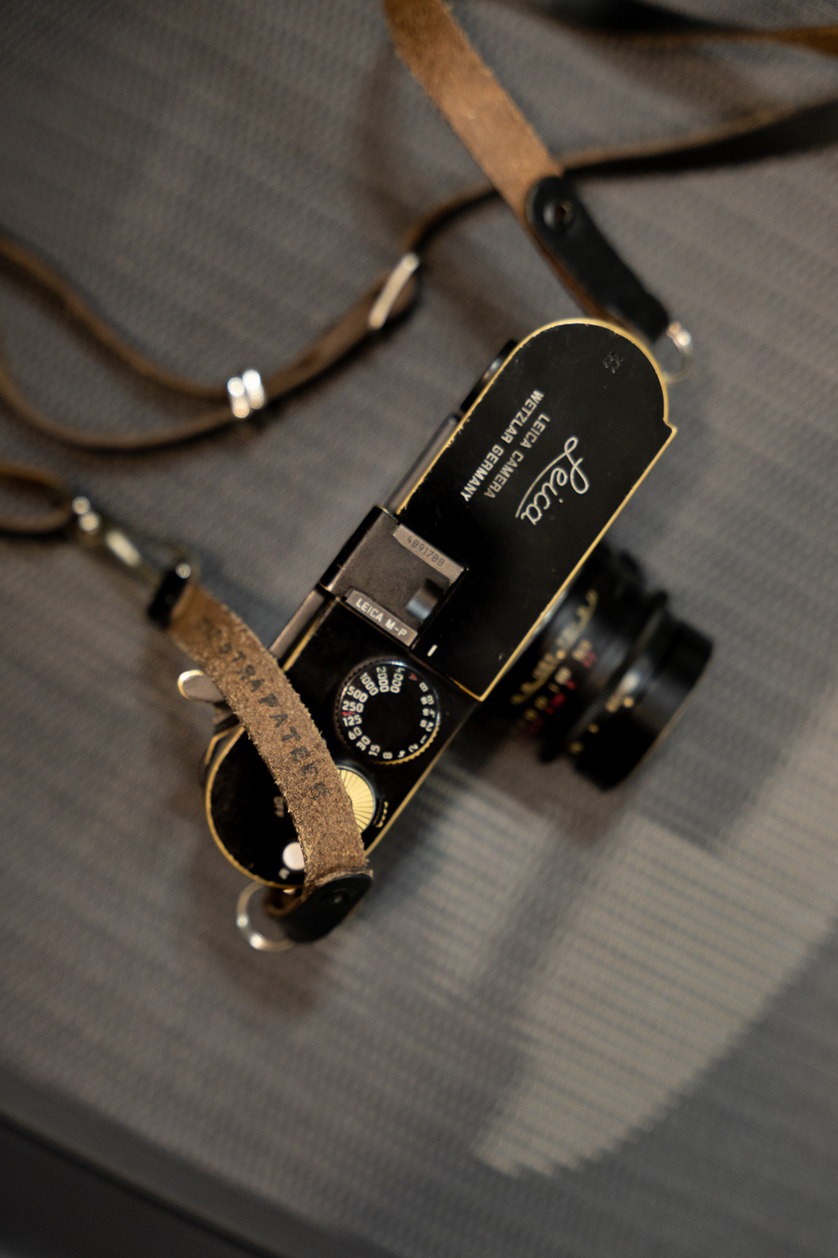 라이카 M-P(Typ 240)의 상판에 새겨진 클래식한 라이카 스크립트 각인과 셔터 스피드 다이얼, 빈티지 가죽 스트랩의 모습.