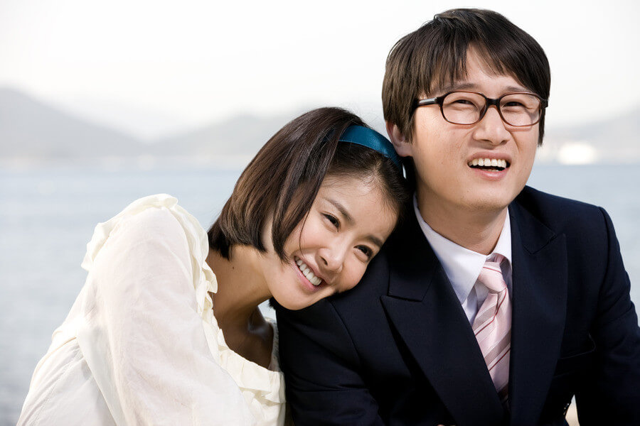 남자의 어깨에 기댄 채 행복하게 웃는 여자와 남자