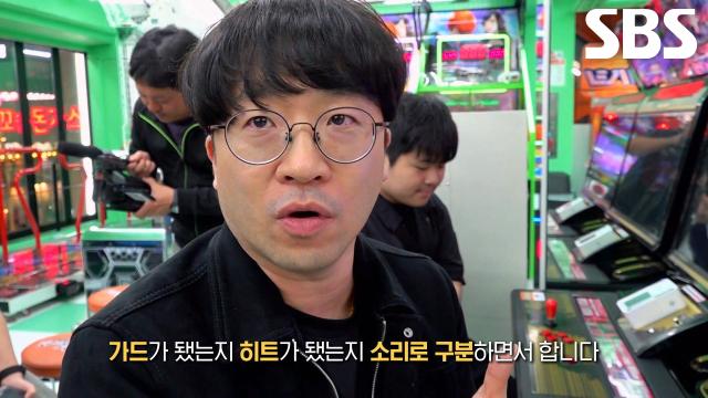 오락실에서 격투 게임 달인이 설명하는 방송 장면