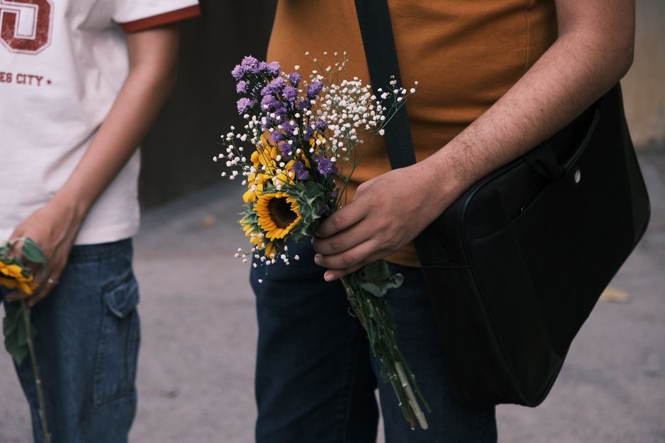 Two individuals casually holding vibrant flower bouquets on a street in Bengaluru.