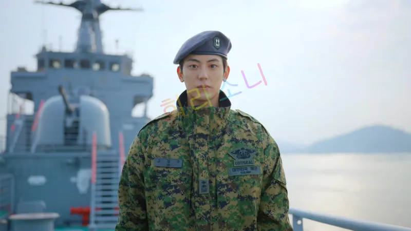 해군 군복을 입은 오강수(이석기)가 함선 위에서 정면을 응시하고 있다. 그는 회색 베레모를 쓰고 있으며&amp;#44; 단정한 표정을 짓고 있다. 배경에는 군함과 바다가 펼쳐져 있다.