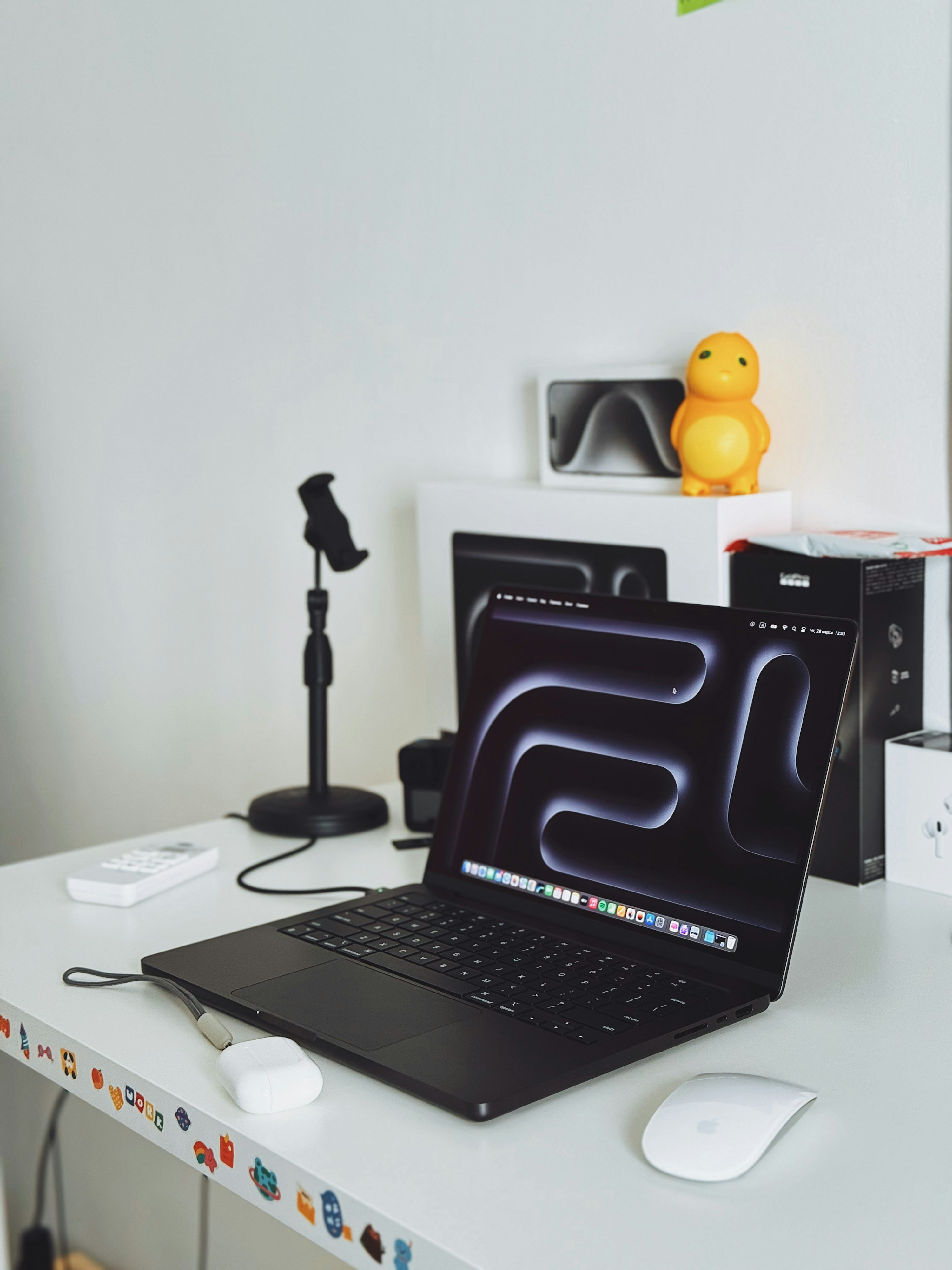 흰 책상 위에 열린 검은색 MacBook과 마우스가 놓인 실제 작업 공간