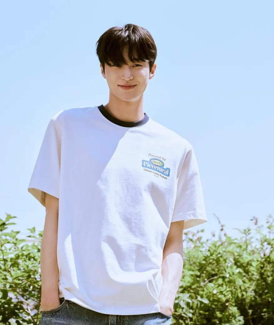 파란 하늘배경 흰티를 입고 청바지 주머니 양측에 손을 꽂고 미소짓고 있는 변우석