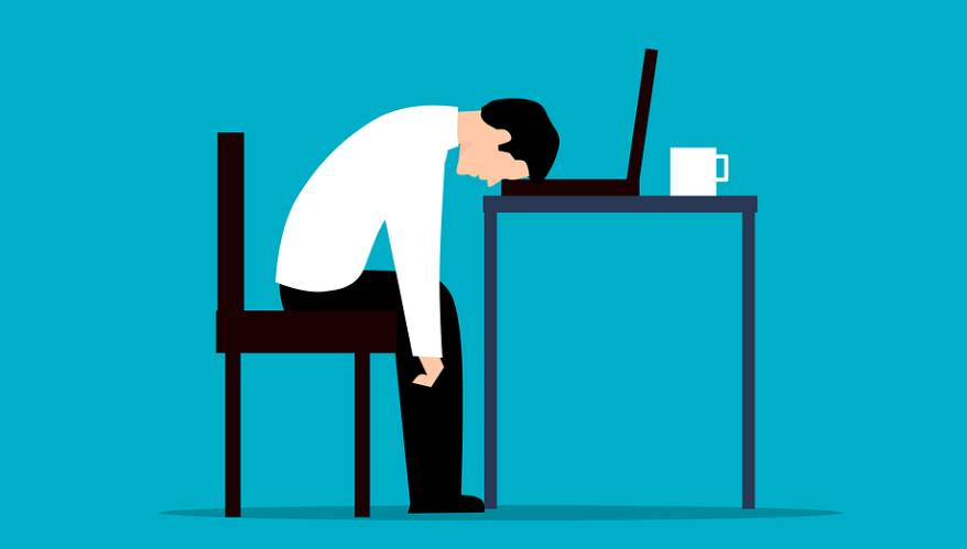 철분 부족 증상으로 피로를 느껴 책상에 머리를 기대고 휴식을 취하는 남성