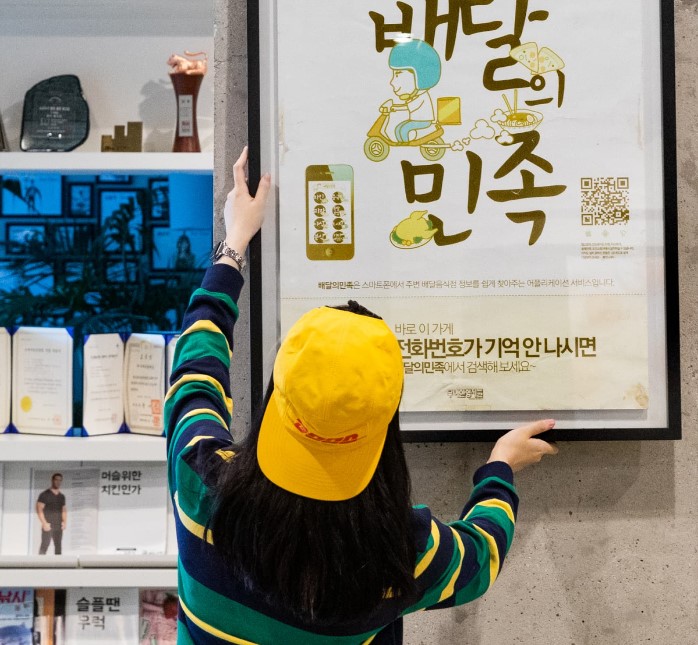 배달의 민족 액자를 걸고 있는 직원 분 (출처:우아한형제들)