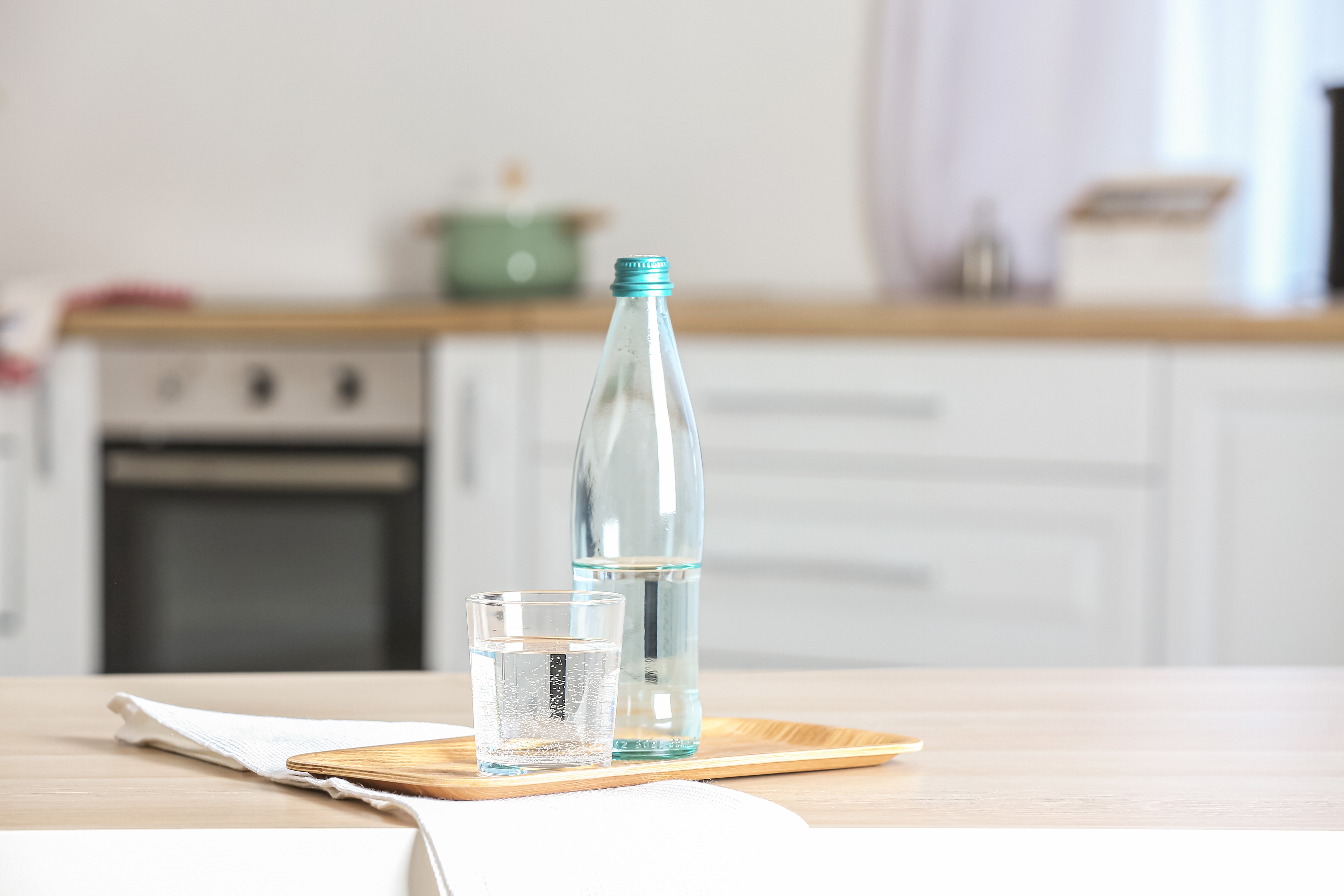 하루 2L 물 마시기의 실천을 상징하는 이미지로, 식탁 위에 놓인 생수병과 투명한 물컵의 모습