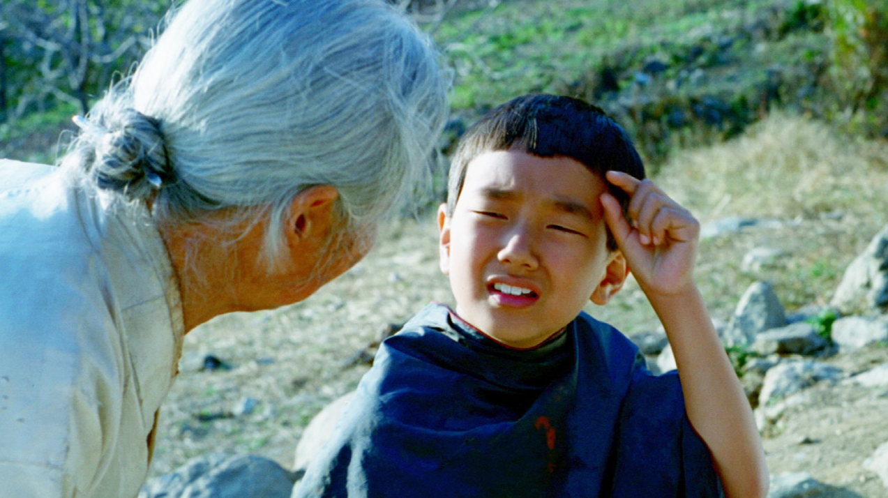 할머니가 몸을 굽혀 다가오는 가운데 상우가 눈물을 흘리며 울고 있는 장면