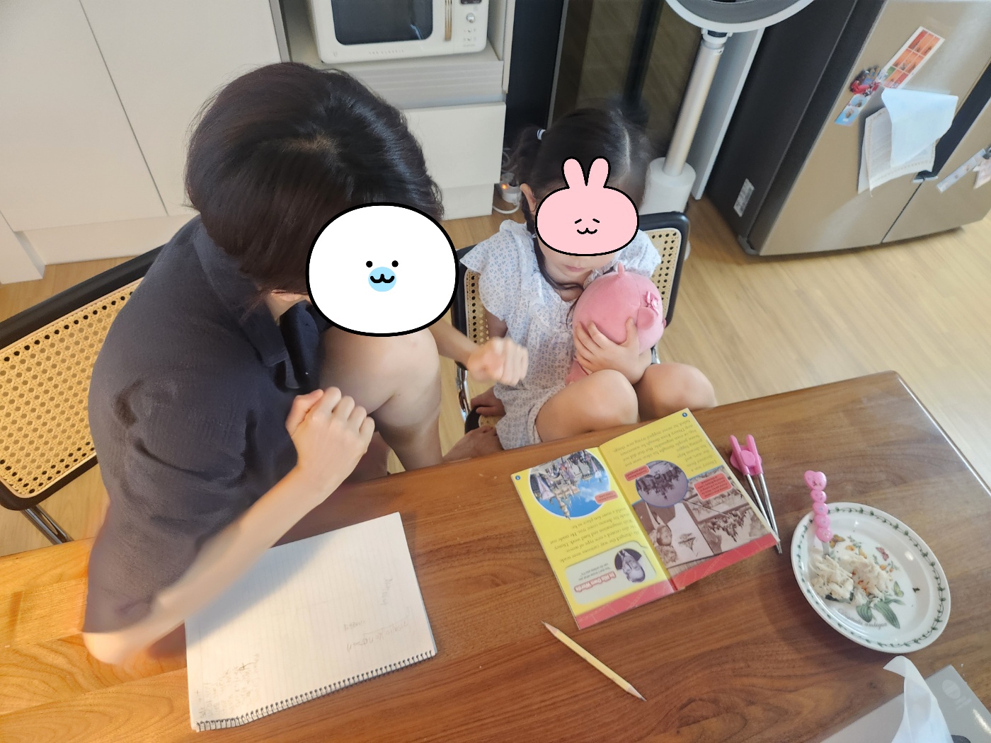 아이가 식탁에서 영어책을 펼쳐놓고 부모와 함께 앉아 있는 일상 모습
