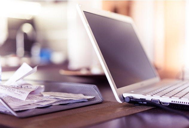 노트북 옆에 정리된 영수증 더미가 있는 책상 풍경.