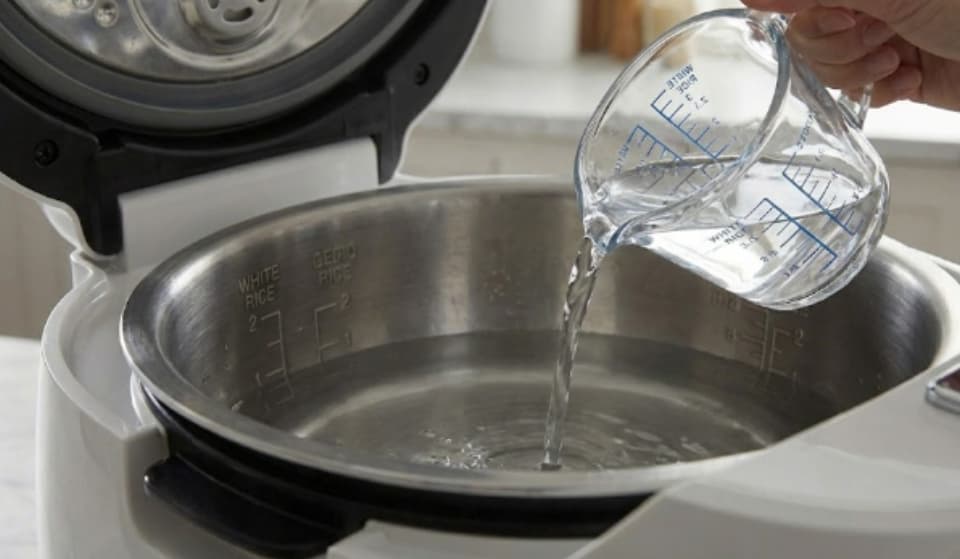 화이트 인테리어 주방에서 밥솥에 물 넣는 사진
