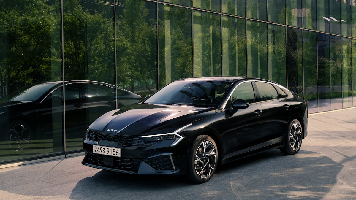 유리 건물 외벽 앞에 주차된 검은색 기아 K5 세단 차량. 연애 프로그램에서 특정 집단을 재단하는 상징으로 사용된 K5.